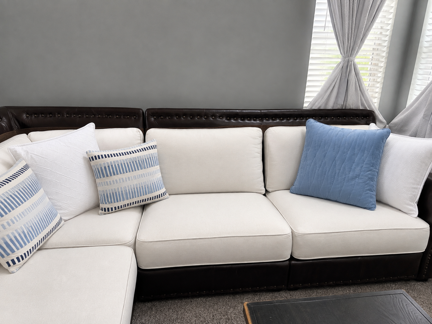 Close view of white linen sectional cushions with blue accent pillows