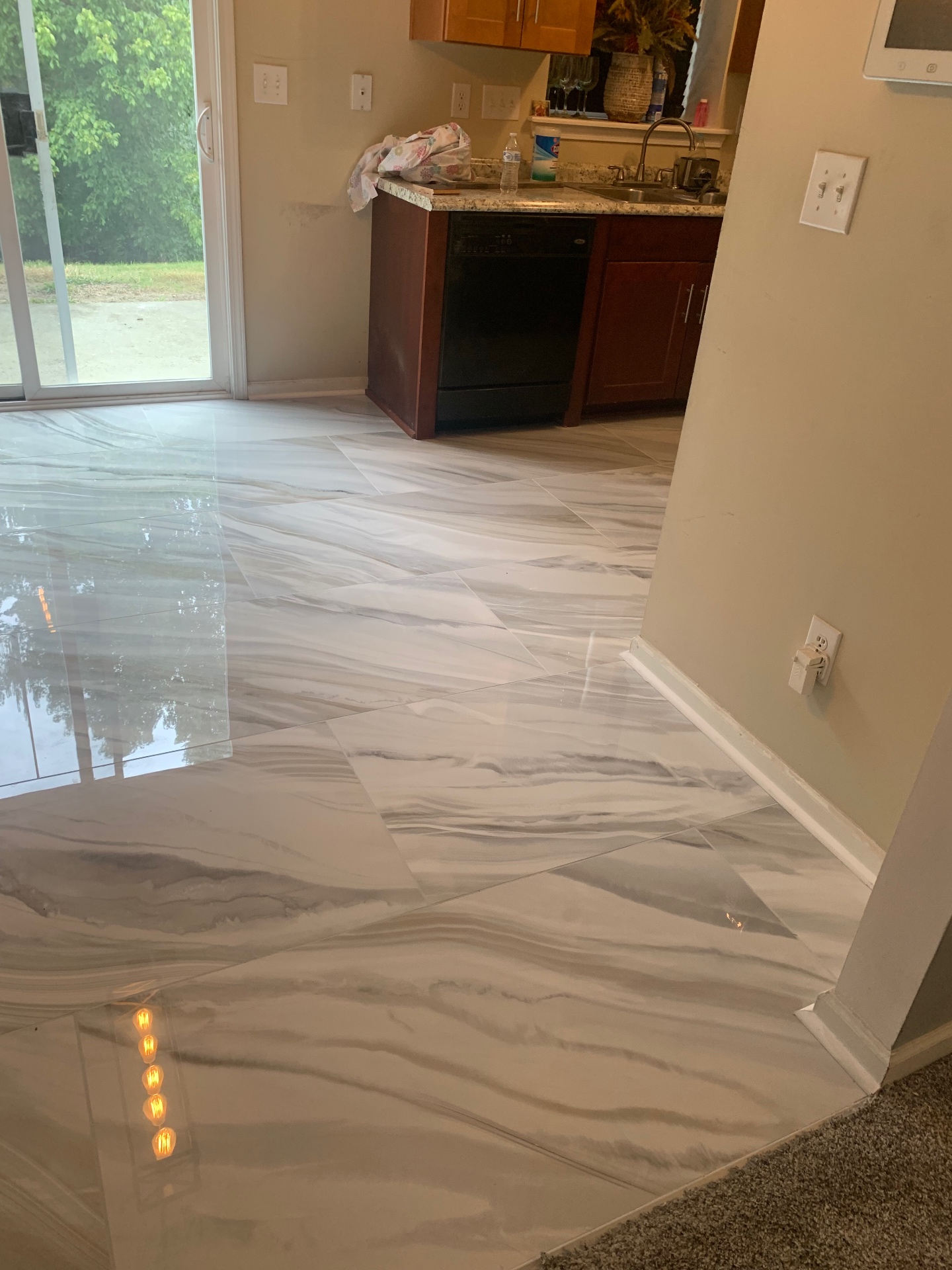 Kitchen and dining area with polished marbled tile meeting carpet