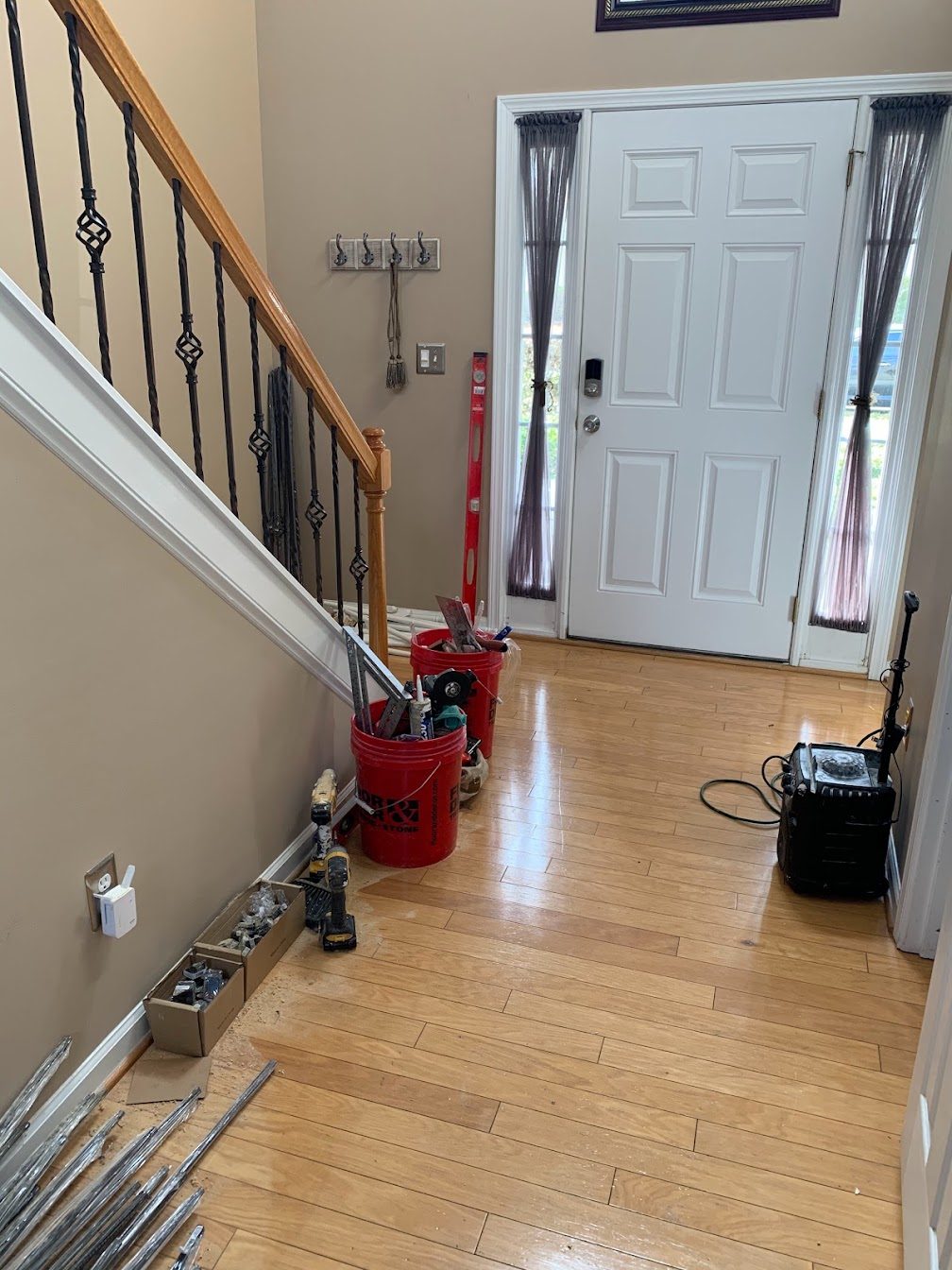 Foyer after with refinished oak flooring, wrought iron balusters and fresh neutral walls