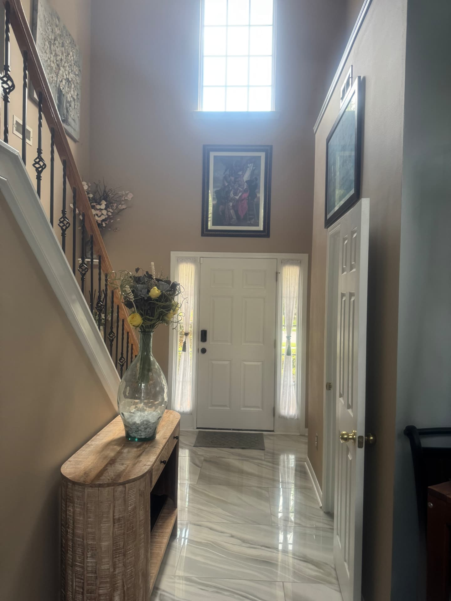 Foyer after with marble tile entry, console table and updated stair railing