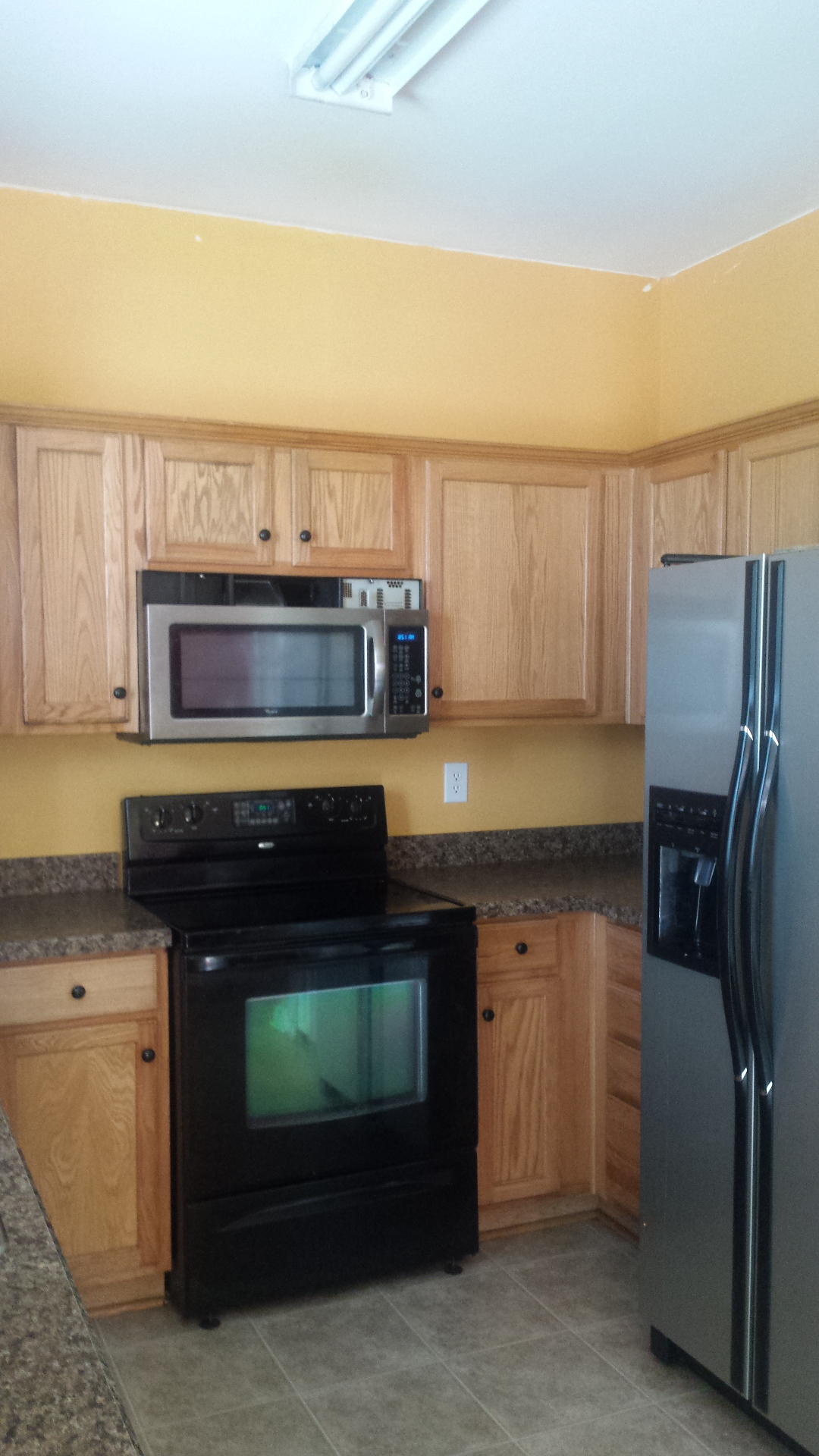 Kitchen before renovation with oak cabinets and yellow walls