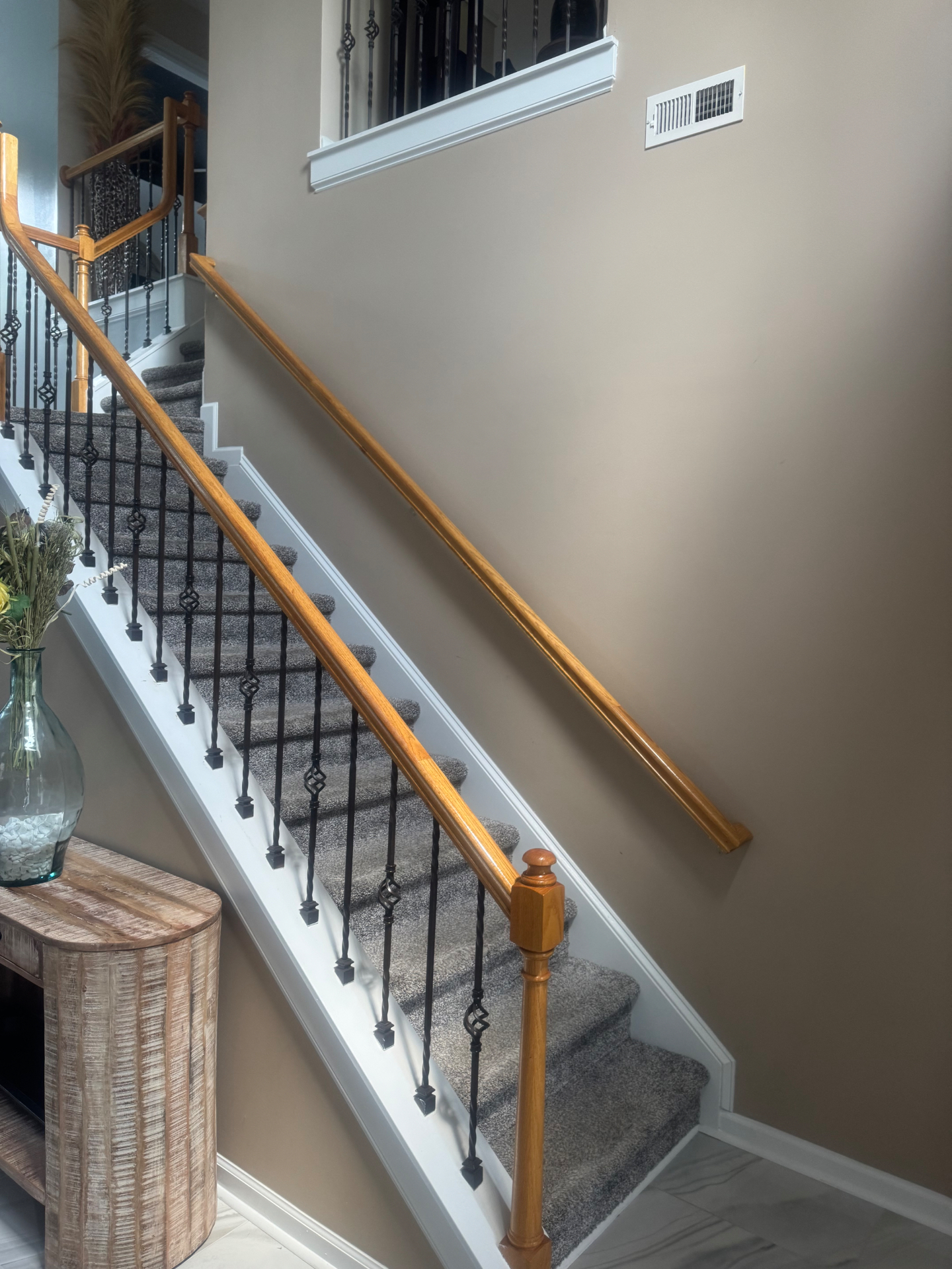 Staircase with oak railing, iron balusters and carpeted treads