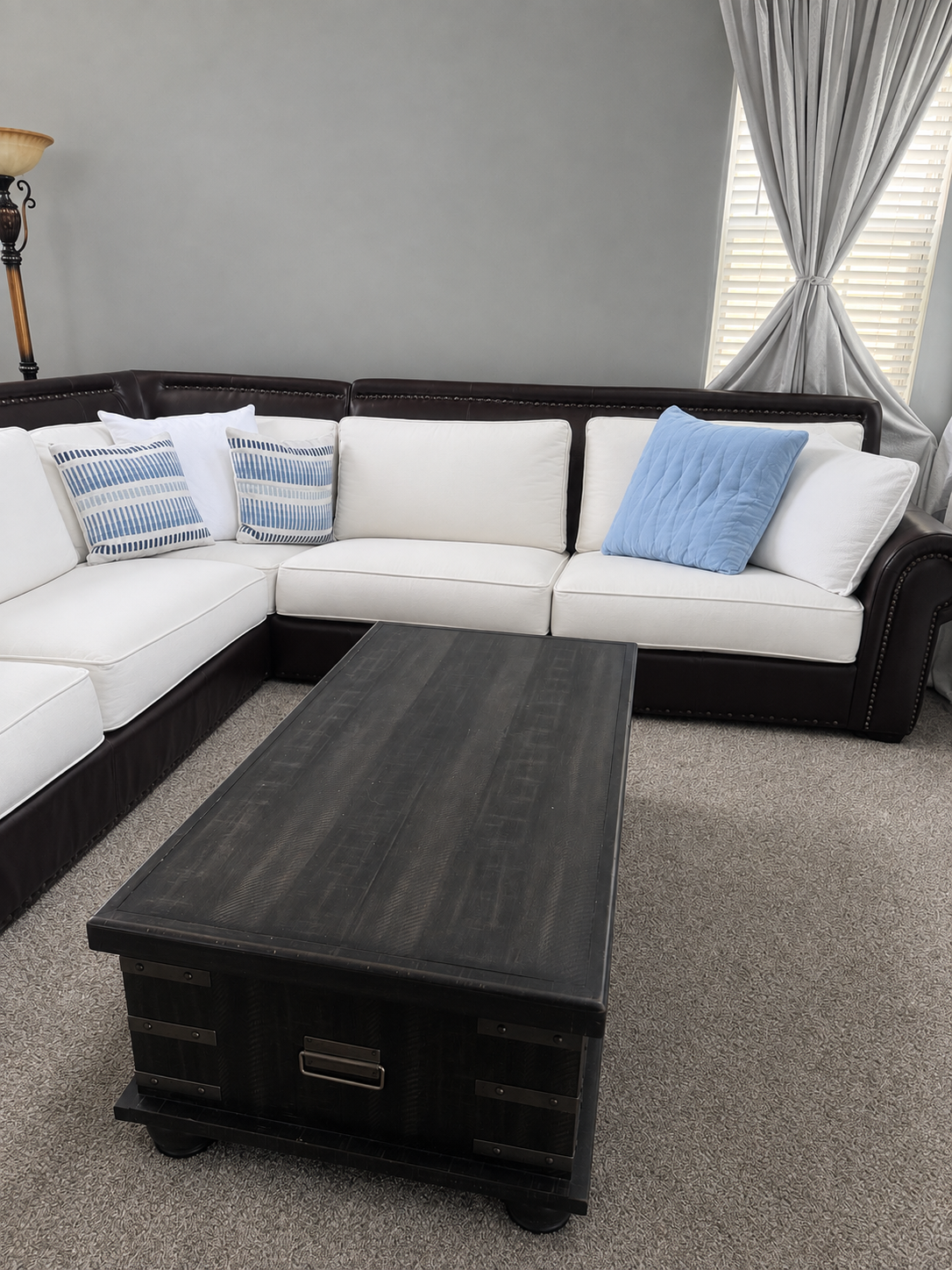 Living room after with crisp white slipcovered sectional, blue accent pillows and dark wood trunk table