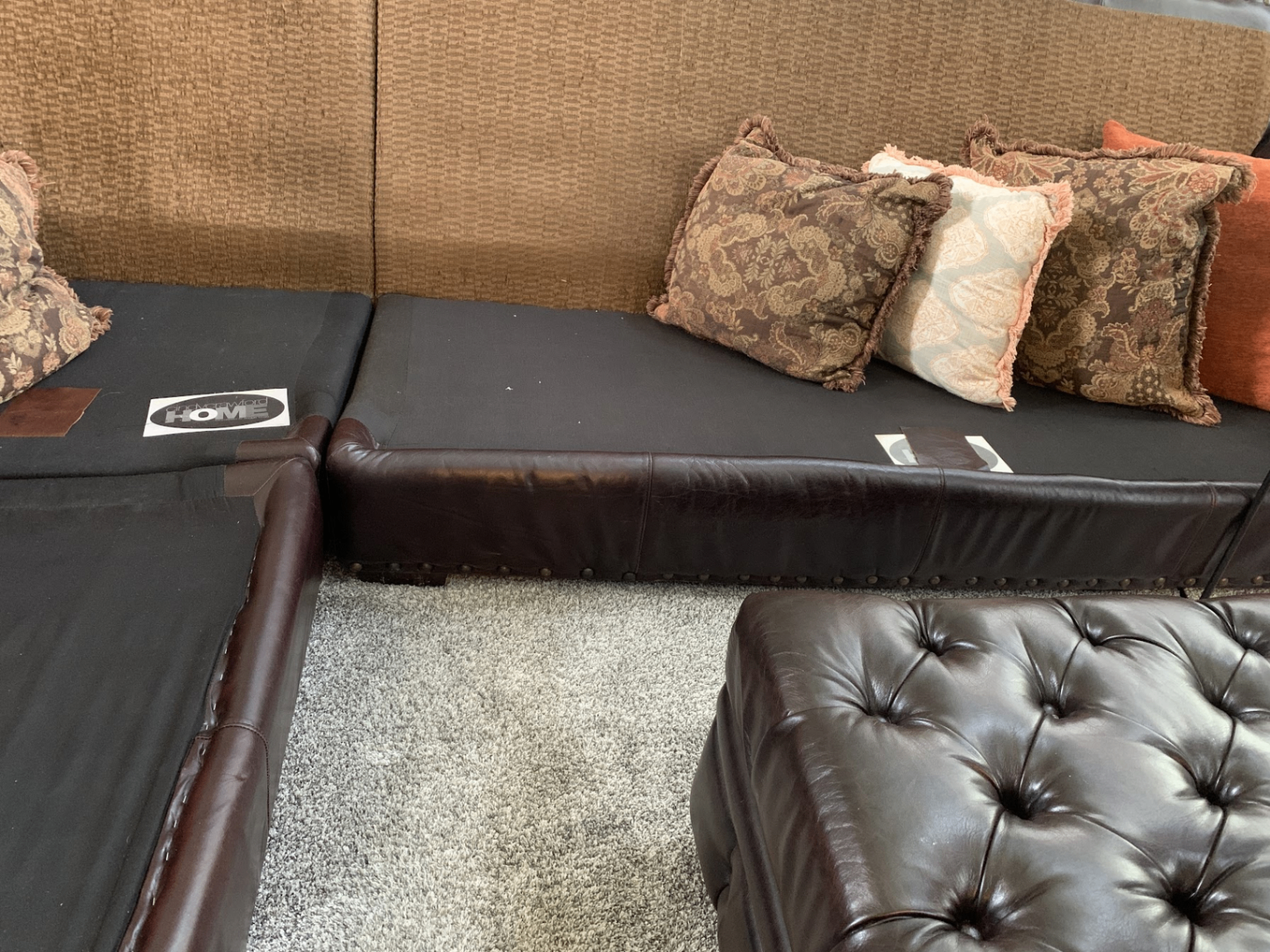 Sectional before with bare black deck, brown leather frame and dated paisley pillows