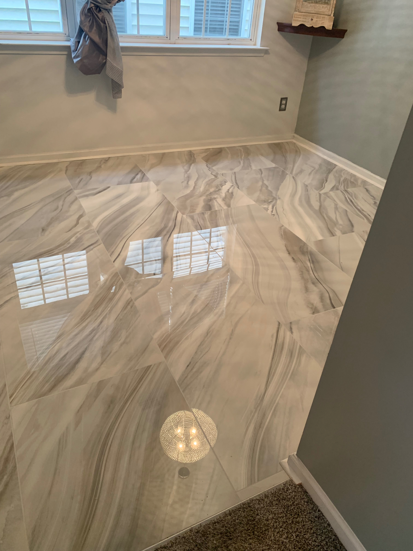 Glossy marbled porcelain tile laid on the diagonal in a soft grey room