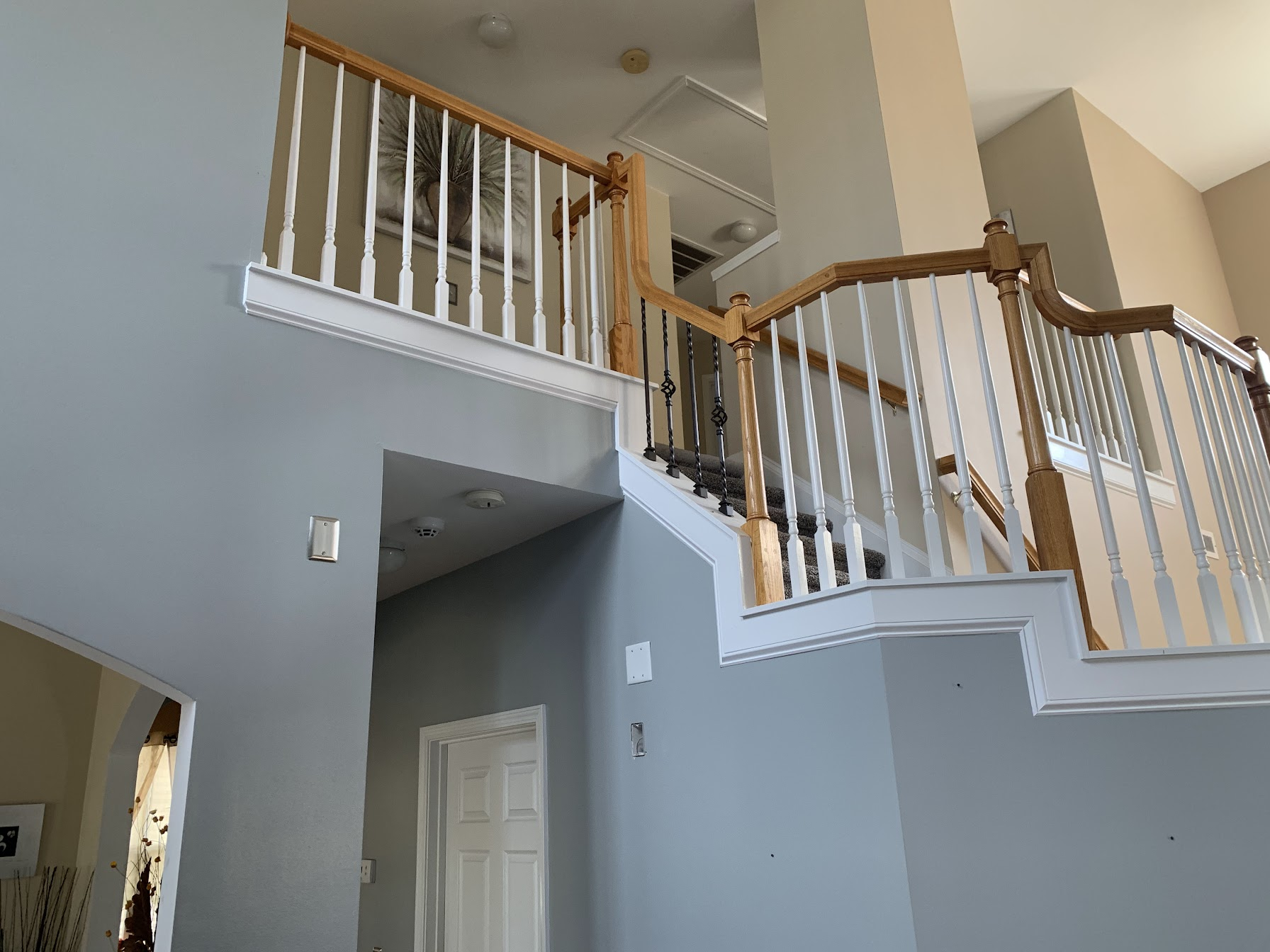 Foyer before with light oak railings and white spindles on the stair landing