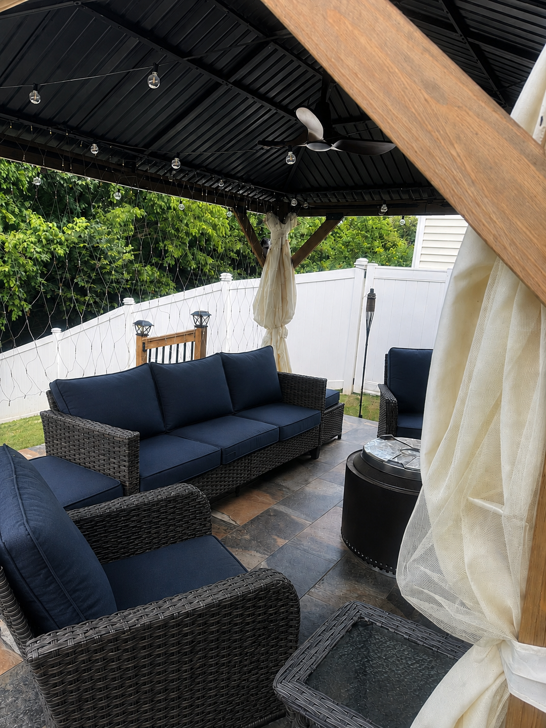 Covered gazebo patio lounge with navy cushioned wicker seating on slate tile